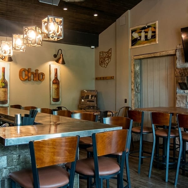 A rustic bar area with high-top tables, bar stools, and a stone fireplace with a TV.
